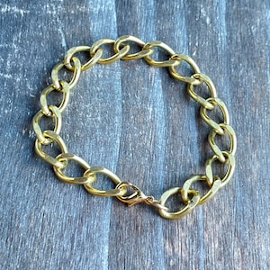 Op de afbeelding: Een gouden kettingarmband met een sluiting. De ketting is gemaakt van dikke, getextureerde schakels.