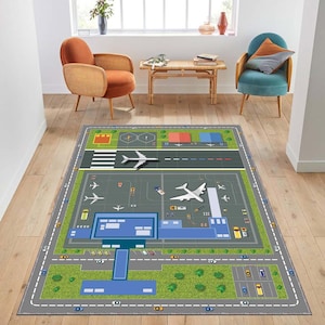 Pode incluir: Um tapete retangular com um design de aeroporto, incluindo pistas, aviões e áreas de estacionamento. O tapete tem uma borda cinza com estradas e estacionamentos, e uma área de gramado verde. O design inclui aviões brancos e vários edifícios de aeroporto.