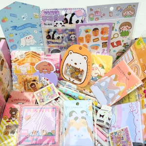 May include: A collection of stationery items including various sticker sheets, notebooks, memo pads, and pens featuring cartoon characters like pandas and bears. The assortment includes colourful packaging with Japanese and Chinese text, small erasers, and decorative paper goods in a variety of pastel and bright colours.