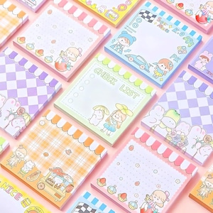 May include: A selection of patterned sticky note pads in various colours. Each pad features illustrations of cartoon characters, food, and decorative elements. Some pads have a checkered pattern, while others have a checklist or blank space for writing.