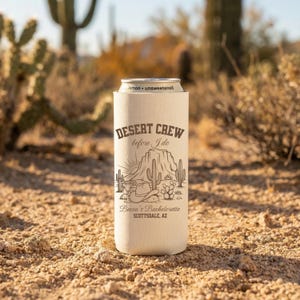 May include: A beige can cooler with the text "Desert Crew before I do" and a desert landscape graphic. The can cooler is holding a silver can labeled "lemon • unsweetened". The text "Becca's Bachelorette Scottsdale, AZ" is also printed on the cooler.