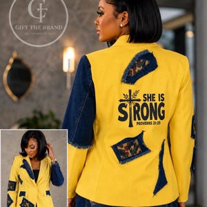 May include: A yellow blazer featuring dark blue denim sleeves and distressed denim patches with camouflage fabric accents. The back displays the black text "SHE IS STRONG PROVERBS 31:25" with a cross graphic. The blazer has a notched lapel and a single button.