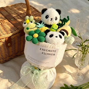 Puede incluir: Un ramo caprichoso con osos panda de peluche, juguetes con forma de fruta verde y amarilla y una gran flor verde. El ramo est&aacute; envuelto en tela blanca y atado con una cinta verde claro. El texto "FAVORITE FLOWER" est&aacute; impreso.