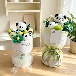 Puede incluir: Dos ramos de pandas de peluche. Uno es blanco con un lazo verde y el texto "FAVORITE FLOWER". El otro est&aacute; envuelto en verde con una etiqueta "Flower Studio". Ambos contienen flores de peluche y otros animales de peluche.