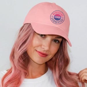 Peut inclure: Casquette de baseball rose clair avec le texte "BISEXUEL ET ÉPUISÉ" dans un motif circulaire. La casquette est de couleur rose uni et possède une visière incurvée. Le chapeau est fait d'une matière douce.