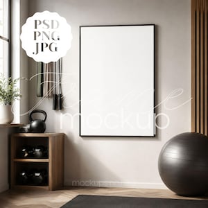 Op de afbeelding: Een ingelijste blanco poster-mockup in een moderne sportschoolomgeving. De afbeelding toont een zwart frame, trainingsapparatuur en een houten opbergunit. Een zwarte oefenbal en een yogamat zijn ook zichtbaar.