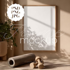 May include: A vertical rectangular wooden frame with a blank white center, positioned on a wall. A rolled gray yoga mat and a pair of light brown dumbbells are placed in front of the frame. The text PSD PNG JPG is visible in the upper left.