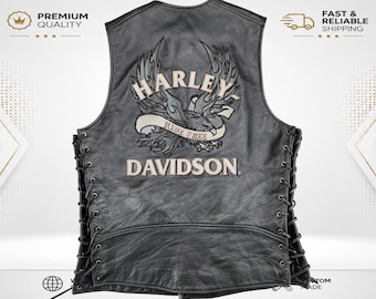 May include: A black leather vest featuring side lacing with black cords. The back displays an embroidered graphic of an eagle with flames and the text Harley-Davidson and Ride Free in light-colored thread against the dark leather surface.