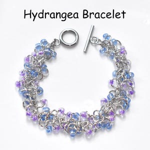 May include: A silver chain bracelet with blue and purple beads. The bracelet has a toggle clasp.