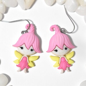May include: A pair of pink and yellow fairy earrings with silver hooks. The fairies have pink hair, white faces, and yellow wings.