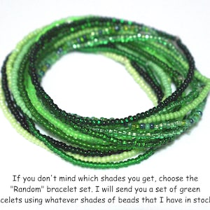 May include: A collection of green beaded bracelets in various shades, from light to dark, are arranged in a circular pattern. The bracelets are made of small, round beads. Text on the image says, "Random" bracelet set.