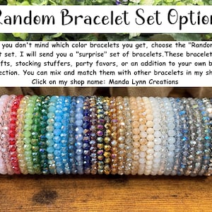 Peut inclure: Une collection de vingt-deux bracelets &eacute;lastiques compos&eacute;s de perles de verre &agrave; facettes multicolores dispos&eacute;es en rang&eacute;e. Le texte ci-dessus indique : Random Bracelet Set Option : If you don't mind which color bracelets you get.