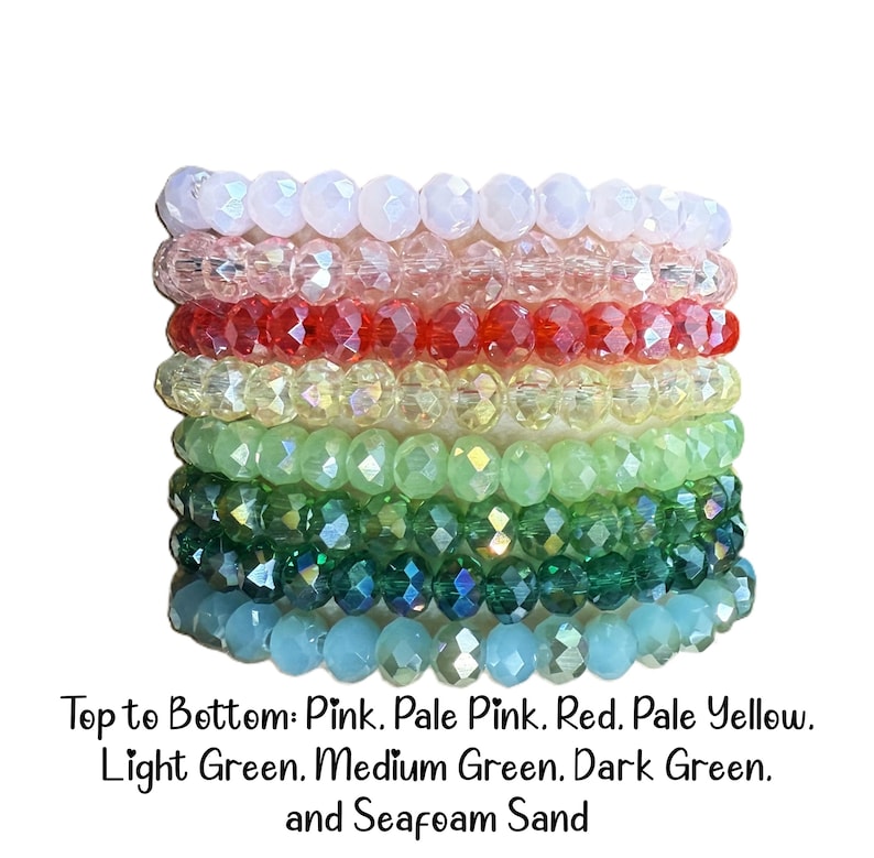 Peut inclure: Une pile de huit bracelets de perles en cristal &agrave; facettes dans un spectre de couleurs. Les couleurs de haut en bas sont rose, rose p&acirc;le, rouge, jaune p&acirc;le, vert clair, vert moyen, vert fonc&eacute; et sable &eacute;cume de mer. Chaque bracelet a des perles.