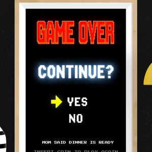 May include: A framed print with a black background features pixelated text in white and red. The text reads "GAME OVER," "CONTINUE?," "YES," and "NO." Below, it says "MOM SAID DINNER IS READY" and "INSERT COIN TO PLAY AGAIN."