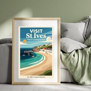 May include: A framed art print featuring a coastal scene with the text "VISIT St Ives England's Stunning Coastline." The artwork depicts a beach, boats, and colorful buildings under a blue sky. The print is part of the "Coastal Collection."
