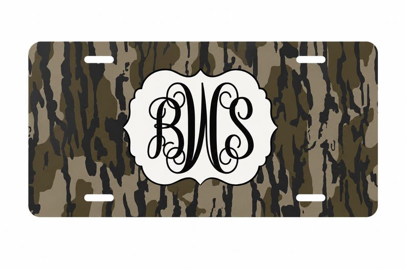 Op de afbeelding: Rechthoekige nummerplaat met een camouflagepatroon in bruin, groen en zwart. Een wit, sierlijk, ovaal embleem in het midden toont het monogram "BWS" in zwart schrift.
