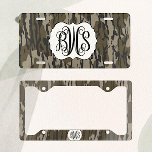Op de afbeelding: Een kentekenplaat en frame set met een camouflagepatroon in bruin, beige en zwart. De kentekenplaat heeft een wit embleem met de zwarte initialen "BVS". De bijpassende lijst heeft hetzelfde camouflagepatroon en de initialen.