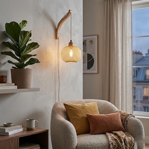 Könnte beinhalten: Eine Pendelleuchte aus geflochtenem Rattan mit einem Holzarm ist an einer strukturierten Wand befestigt. Das Licht hängt über einem cremefarbenen Sessel mit senf- und rostfarbenen Kissen. Eine Topfpflanze und Kunstwerke vervollständigen das gemütliche Interieur.