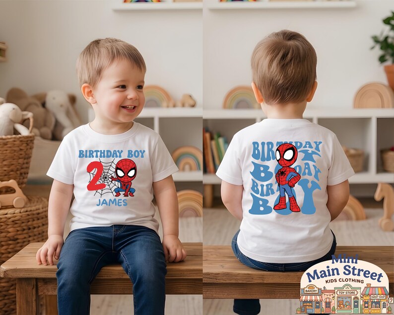 May include: White t-shirt featuring a Spider-Man graphic for a 2nd birthday. The front displays "BIRTHDAY BOY", the number "2", a web, and the name "JAMES". The back has a Spider-Man graphic and "BIRTHDAY BOY" in blue.