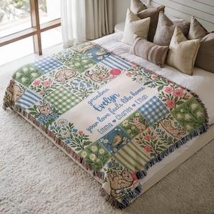 May include: A woven throw blanket featuring a patchwork design of cats, flowers, and blue gingham patterns. The center includes the text: grandma Evelyn, your love feels like home, Emma, Charles, Ethan. The blanket has a fringed edge finish.