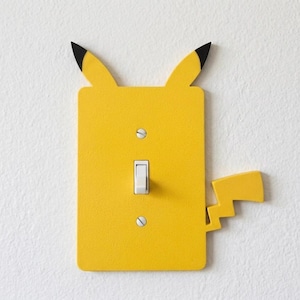 May include: A white ceramic mug with a black handle and the text "But First, Coffee" in a bold, black font. The mug is set against a blurred background, suggesting a cozy setting. The mug appears to be approximately 4 inches tall.