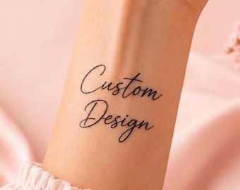 Könnte beinhalten: Ein temporäres Tattoo auf der Haut mit dem schwarzen Schriftzug Custom Design. Die Beschriftung ist in einer fließenden Schreibschrift gehalten, wobei das Wort Custom in der oberen Zeile und das Wort Design direkt darunter steht.