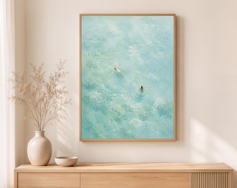 May include: A framed wall art print featuring an oil painting of two figures swimming in clear, light blue water. The artwork displays textured brushstrokes in shades of turquoise, aqua, and white, capturing the movement of ripples and light.