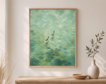 May include: A framed wall art print featuring a painting of two zebras wading through shallow, light green water. The artwork displays ripples around the zebras and sunlight reflecting off the water surface, all enclosed in a light wood frame.