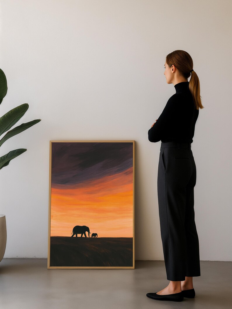 May include: Framed art print featuring a silhouette of two elephants against a vibrant sunset sky. The artwork showcases a warm palette of orange, yellow, and purple hues, with a simple, elegant design. The frame is a natural wood color.