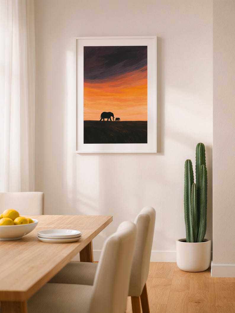 May include: Framed art print featuring a silhouette of two elephants against a vibrant sunset sky. The artwork showcases a warm palette of orange, yellow, and purple hues, creating a serene and natural scene. The print is displayed in a white frame.