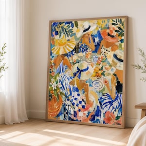 May include: A framed painting depicting a group of figures wearing sun hats and patterned clothing gathered around a table with plates and fruit. The artwork features a vibrant colour palette of blue, yellow, orange, and white with visible brushstrokes.