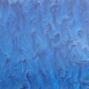 Op de afbeelding: Een close-up van een blauwe, gemarmerde, abstracte hars plaat. De hars heeft een marmerachtige, bewolkte uitstraling.