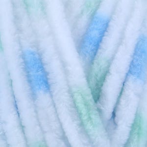 Op de afbeelding: Close-up van een zacht, getextureerd garen in wit, blauw en groen. Het garen ziet er pluizig en zacht uit, met een subtiele kleurovergang. De afbeelding benadrukt de textuur en kleurvariaties van het garen, geschikt voor brei- of haakprojecten.