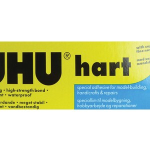 May include: Yellow and blue packaging for UHU Hart glue. The packaging features the UHU logo and the text "fast-setting high-strength bond, transparent waterproof, hurtigt hærdande meget stabil, transparent vandbestandig". The packaging also features the text "special adhesive for model-building, handicrafts & repairs, speciallim til modelbygning, hobbyarbejde og reparationer".