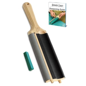 May include: A wooden sharpening paddle with a light wood handle and a grey and black sharpening surface. A small, green sharpening compound stick is next to the paddle. A book titled "BEAVER CRAFT Sharpening Guide" is in the background.
