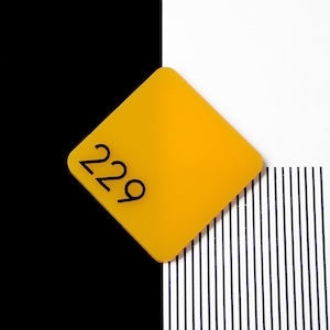 Peut inclure: Un panneau carré jaune avec le numéro 229 imprimé en noir sur un fond rayé blanc et noir.