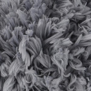 Puede incluir: Primer plano de una tela gris suave y texturizada. El material tiene una apariencia peluda con muchos hilos de diferentes longitudes, creando un aspecto afelpado y acogedor. Las fibras están densamente empaquetadas, dando a la tela una sensación completa y voluminosa.