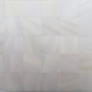 以下が含まれることがあります： 白く正方形のタイルが敷き詰められた表面のクローズアップ。タイルは格子状に配置され、それぞれが光を反射し、繊細な真珠光沢を生み出しています。全体的な効果はクリーンでミニマリストです。