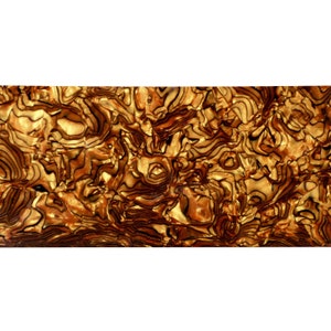 Puede incluir: Primer plano de un material decorativo con un patrón arremolinado. El material tiene una mezcla de colores dorados, marrones y negros, creando una apariencia texturizada y orgánica. El diseño se asemeja a la veta de la madera o a una piedra natural.