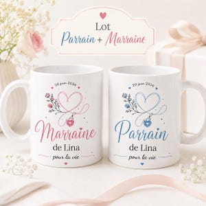 Può includere: Due tazze in ceramica bianca con un motivo floreale a forma di cuore. La tazza a sinistra presenta il testo rosa Marraine de Lina pour la vie, quella a destra il testo blu Parrain de Lina pour la vie, entrambe datate 20 juin 2026.