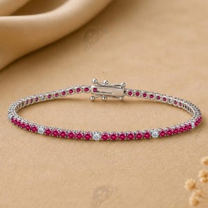 May include: A silver-toned tennis bracelet featuring a continuous row of small, round, vibrant pink stones interspersed with occasional clear, colorless stones, finished with a secure metal box clasp closure mechanism.