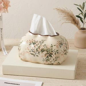 Elegante funda de cerámica color crema con estampado floral para caja de pañuelos, borde festoneado con ribete marrón, decoración vintage para el hogar.