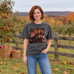 K&ouml;nnte beinhalten: Ein anthrazitfarbenes Kurzarm-T-Shirt mit einem Grafikdruck von Katzen, die sich um einen Sarg versammeln. Das Design enth&auml;lt den Text "Flowers for Kitty" und "Coffin Buddies" mit einer d&uuml;steren Szene von Katzen in formeller Kleidung.