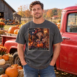 May include: A charcoal gray short-sleeve t-shirt featuring a rectangular graphic print of a cat dressed as a witch holding a broom and a pumpkin filled with candy. The text reads Memories to Cherish and Grandma Goes Halloween '88.