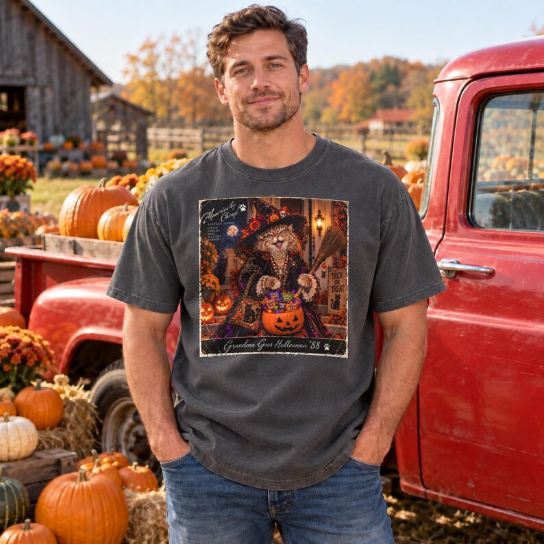 May include: A charcoal gray short-sleeve t-shirt featuring a rectangular graphic print of a cat dressed as a witch holding a broom and a pumpkin filled with candy. The text reads Memories to Cherish and Grandma Goes Halloween '88.