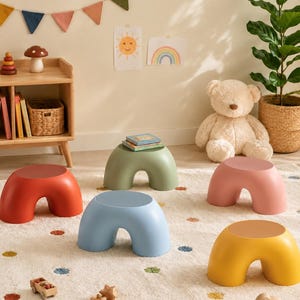 Può includere: Una collezione di cinque sgabelli a forma di arco in colori solidi, tra cui rosso, verde salvia, rosa polvere, azzurro e giallo senape. Ogni sgabello presenta una superficie superiore liscia e arrotondata e due gambe larghe e curve.