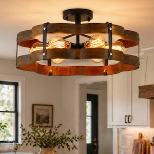 May include: A rustic, circular ceiling light fixture with exposed Edison bulbs. The light has a dark metal frame and wooden accents, creating a warm, inviting glow. The fixture is mounted in a modern kitchen with white cabinets and a marble countertop.