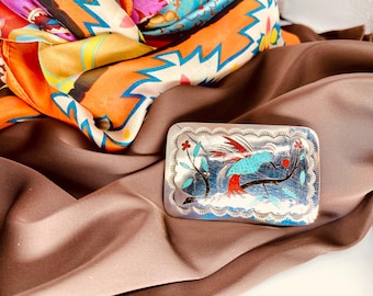 Hebilla de cinturón de plata esterlina con forma de colibrí, de estilo suroeste, con incrustaciones de turquesa y coral, adornada con una rama de árbol y flores en flor.