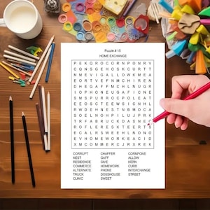 K&ouml;nnte beinhalten: Ein wei&szlig;es Blatt Papier mit einem Wortsuchr&auml;tsel mit dem Titel Puzzle # 15 HOME EXCHANGE, das ein Buchstabenraster und eine Liste der zu suchenden W&ouml;rter enth&auml;lt. Ein roter Stift liegt auf dem Raster, umgeben von verschiedenen Buntstiften.
