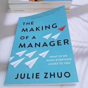 May include: A light blue book titled The Making of a Manager by Julie Zhuo. The cover features white paper airplanes flying in formation, with one red paper airplane, and the subtitle What to Do When Everyone Looks to You in white text.